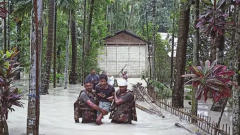 BBC Army personnel wade through flood waters to reach stranded persons