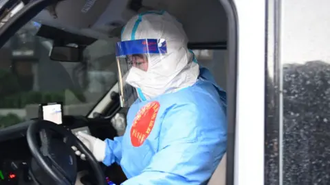 Getty Images A member of a medical assistance team gets into an ambulance vehicle to transfer Covid-19 patients to a hospital in Shanghai, China.