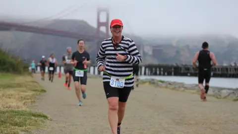 Finisherpix Sally Orange running with Golden Gate Bridge in background