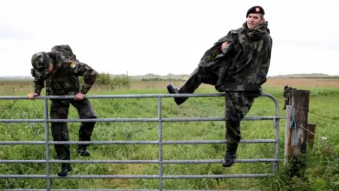 AFP/Getty Images Irish soldiers search fields as part of a security operation near the entrance to Mr Trump's golf resort