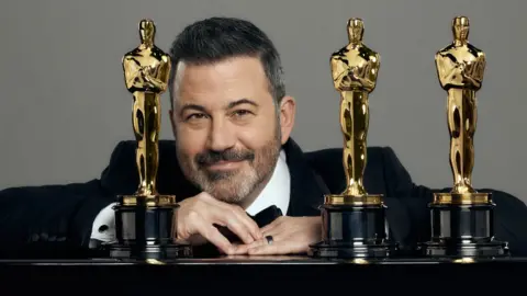 Getty Images Jimmy Kimmel posing with Oscar statuettes
