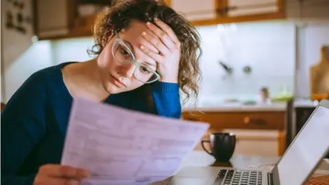 Getty Images Woman looks at bills