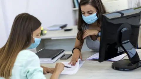 Getty Images Two people sitting at a desk discussing paper work