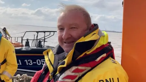 Andrew Turner/BBC Paddy Lee in his RNLI uniform on board a lifeboat