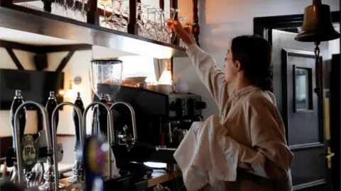 Reuters A woman cleaning wine glasses behind a bar