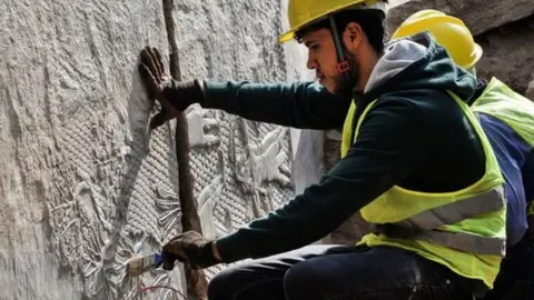 An Iraqi worker excavates a rock-carving relief found at the Mashki Gate, from the ancient Assyrian city of Nineveh, on the outskirts of Mosul, 19 Oct 22