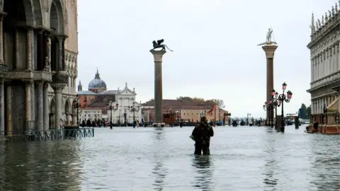 Reuters A man stands in water at the flooded St Mark's Square during exceptionally high water levels in Venice, Italy, 13 November 2019