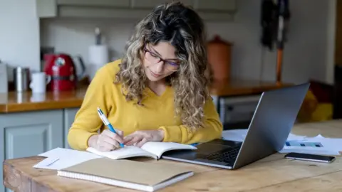 Getty Images Woman working from home at kitchen table.