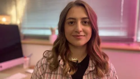 Mousumi Bakshi/BBC Young woman smiling at camera in an office