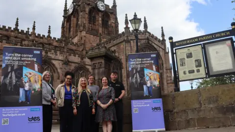 Supplied A group of men and women stand together outside a large Cathedral, flanked either side by two purple banners