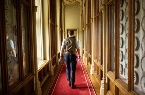 Antonio Olmos Fjodor walks down a long corridor at Windsor Castle