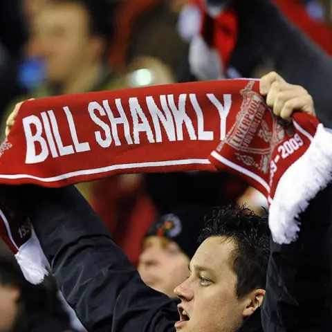 Getty Images A Liverpool fan holds up a red "Bill Shankly" scarf in the crowd at Anfield 