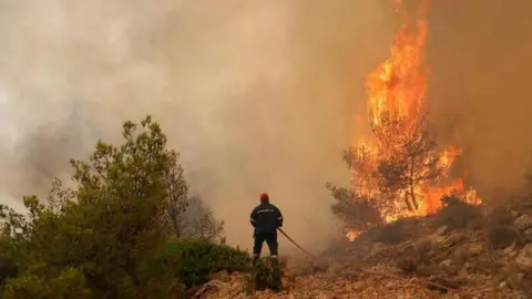 Reuters A firefighter tackles a wildfire in a fire near Athens, Greece. Photo: 19 July 2023