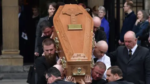 Getty Images Mourners watch as the coffin of journalist Lyra McKee is taken out of the church after the funeral at St Anne's Cathedral on 24 April 2019 in Belfast, Northern Ireland.