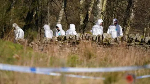 PA Media Forensic officers examine the site in Aberfeldy where Mr Low was shot