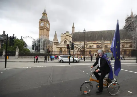 Hannah McKay/REUTERS A protester wears a Boris Johnson face mask as he rides a tricycle.