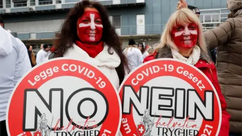 Reuters Demonstrators hold placards as they gather to protest against a planned coronavirus disease (COVID-19) law of the Swiss government in Zurich, Switzerland November 20, 2021