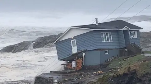 A house looks about to fall into the sea