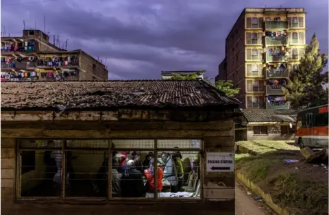 AFP People packed in a small building against a backdrop of dark and grey skies.