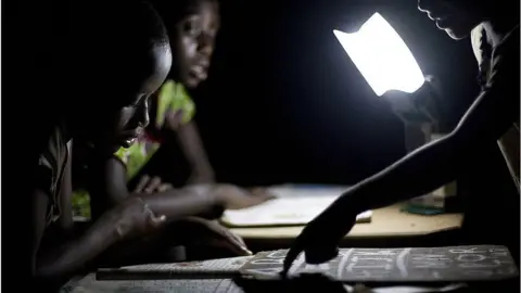 Getty Images Ghanian students study at night using smart LED lanterns provided by Empower Playgrounds.