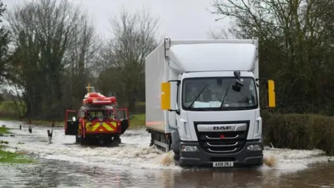 Getty Images Hereford Fire and Rescue test the depth of flood water in the village of Hampton Bishop in Herefordshire, western England