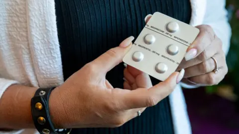 Getty Images Woman holding pills