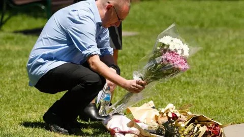 Getty Images A man places flowers near a plaque honouring the victims of the incident
