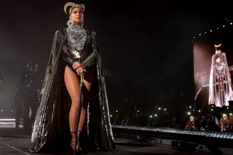 Getty Images Beyoncé performs in an outfit inspired by Queen Nefertiti at the Coachella festival in California (14 April 2018)