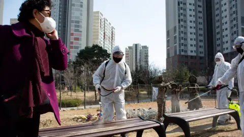 EPA Local residents spray disinfectant in their neighbourhood as a precaution against the coronavirus outbreak, in Seoul, South Korea, 23 March 2020