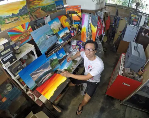 Malcolm Jitam Man with his paintings in Malaysia
