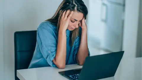 Getty Images woman at computer with head in hands