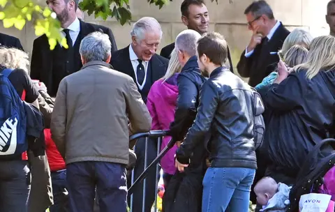 Getty Images King Charles III talks to wellwishers in the garden area set aside for floral tributes outside the Palace of Holyroodhouse in Edinburgh on 12 September 2022