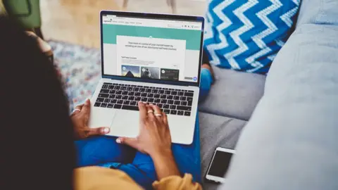 NHS Female on computer on sofa