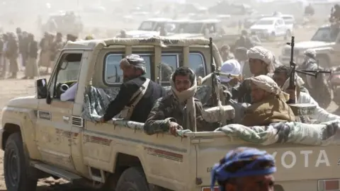 Houthi supporters in the back of a vehicle with guns