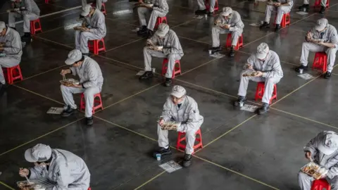 Getty Images Workers eating during lunch break at the Dongfeng Honda plant in Wuhan in China's central Hubei province