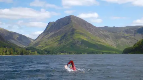 George Taplin George Taplin swims in front of large hill