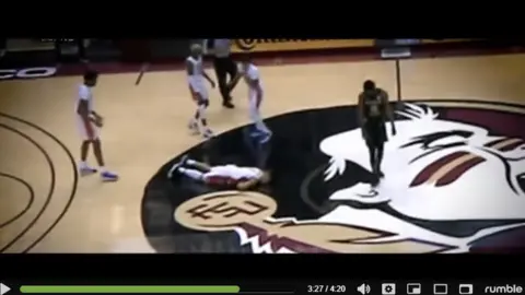 Rumble screenshot from video of basketball player face-down on floor with team mates surrounding him