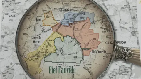 Martel Maides Auctions A magnifying glass focuses in on a section of a map of Guernsey in this montage image. The words 'Fief Fauville' can be seen, along with 'St Sampson' and borders around different areas of the island.