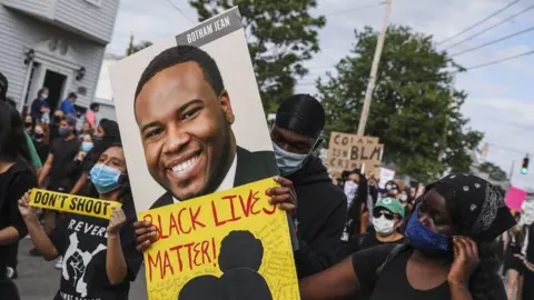 Getty Images A demonstrator holds a sign for Botham Jean while marching during a demonstration on June 9, 2020