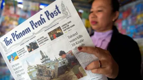 AFP A Cambodian vendor reads the Phnom Penh Post newspaper at her newstand in Phnom Penh on May 7, 2018. The newspaper hailed as Cambodia"s last independent English daily has been sold to a Malaysian investor with apparent business links to premier Hun Sen, rattling a journalist community that has been battered by the strongman ahead of elections.