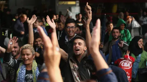 Getty Images Migrants arriving with approximately 800 others on a train from Hungary react to the welcoming cheers of onlookers at Munich