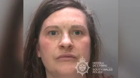 South Wales Police A mugshot of a woman with messy brown hair. She is looking at the camera with a neutral expression.