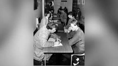 Getty Images Archive shot of men sat at desks, being interviewed by police as part of the police investigation