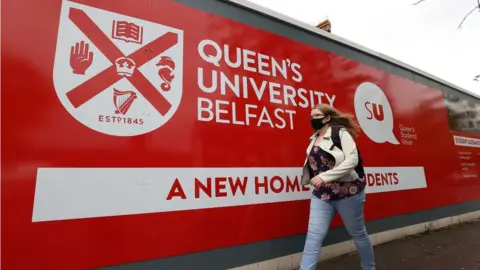 Liam McBurney/PA Wire Student walking past QUB sign