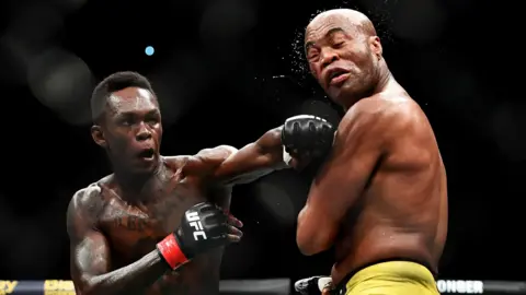 Israel Adesanya (left) aims a blow at Anderson Silva