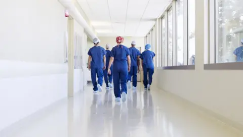 Getty Images Surgical team walking down hospital corridor - stock photo