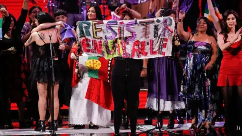 Getty Images Singers with Chilean artist Mon Laferte show a banner reading 'Resist on the Street' at a concert last year