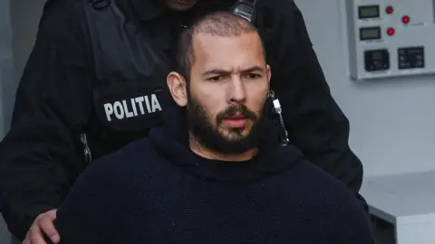 Reuters Andrew Tate escorted by police officers outside the headquarters of the Bucharest Court of Appeal, in Bucharest, Romania, February 1, 2023.