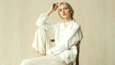 Woman models white button-down shirt