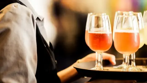 Getty Images Waiter holding tray of drinks